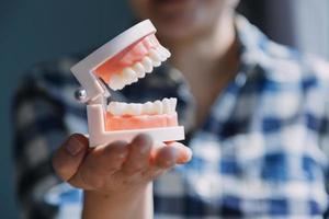 concepto de estomatología, retrato parcial de una chica con fuertes dientes blancos mirando la cámara y sonriendo, con los dedos cerca de la cara. primer plano, de, mujer joven, en, dentista, estudio, adentro foto