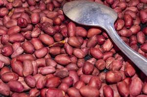 Frying peanuts, a woman's hand stirring peanuts in a frying pan, close-up. photo