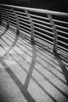 Black and white image of bridge handrails with hard shadow. photo