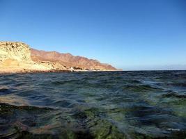 Scenic view of red sea against sky and mountains photo