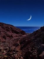 vista panorámica del mar rojo por la noche con luna llena sobre el mar y las montañas foto