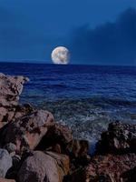 vista panorámica del mar rojo por la noche con luna llena sobre el mar y las montañas foto