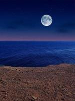 Scenic view of red sea at night with full moon above the sea and mountains photo