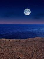 vista panorámica del mar rojo por la noche con luna llena sobre el mar y las montañas foto