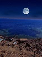 vista panorámica del mar rojo por la noche con luna llena sobre el mar y las montañas foto