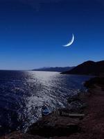 vista panorámica del mar rojo por la noche con luna llena sobre el mar y las montañas foto