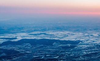 beautiful pink sunset from above, over winter terrain photo