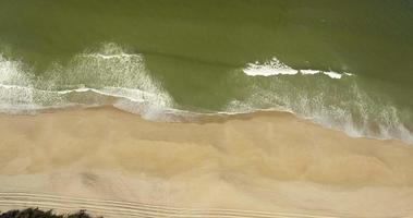 vagues éclaboussant sur la côte sablonneuse de gale, près du camping praia da gale au portugal, ralenti - tir de drone aérien video