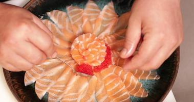 placage de nourriture - chef avec une cuillère à café ajoutant des caviars rouges autour de la rose de saumon sur une assiette ronde. - prise de vue en plongée video
