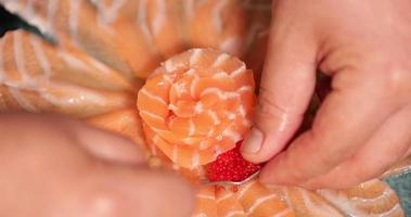 elegante presentación de sashimi - chef de sushi arreglando las finas lonchas de sashimi de salmón fresco en forma de flor con caviar rojo en un plato - toma en ángulo alto video