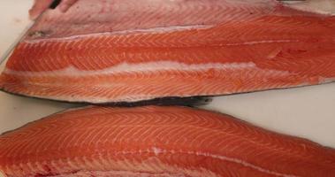 coltello raschiatura su superiore di salmone carne nel un' bianca tavolo. - vicino dall'alto verso il basso tiro video