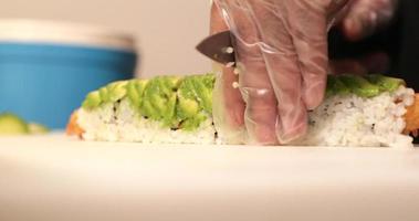 chef cortando os rolos de sushi com camarão tempura frito e abacate verde. - tiro de perto video