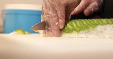 skivning tempura räka sushi rulla med avokado skivor på topp - stänga upp, långsam rörelse video