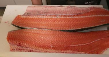 un chef puso el filete de salmón fresco en la tabla de cortar y se preparó para cortar carne en la cocina para sushi. - fotografía de cerca video