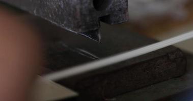 cortando liga elástica em tiras com cortador de máquina em uma fábrica de costura - pandemia de covid-19 - closeup pan à esquerda