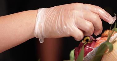 Chef Putting Fresh Flowers On The Platter Of Sushi Rolls, Salmon Sashimi, And Maki Before Serving.  - close up shot video