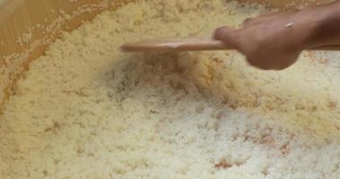 Spreading Sushi Rice With Vinegar Using A Wooden Spoon - high angle slowmo shot video