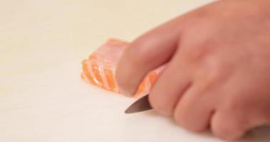 chef habilidoso cortando finamente a carne fresca de salmão usando uma faca afiada em uma tábua branca. - close-up, câmera lenta video