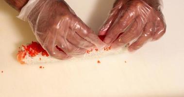 Chef Putting And Spreading Red Caviars On Top Of Salmon Sushi Roll. - high angle shot video