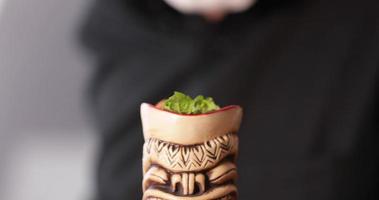 Camarero agregando hojas de menta a un cóctel en tiki de madera - un primerísimo plano video
