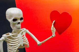 Artificial human body skeleton with a paper heart icon in hand photo