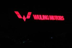 Bekasi, Indonesia in July 2022. The WULING MOTORS logo shining brightly at night against the dark night sky. photo