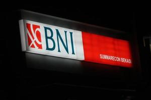 Bekasi, Indonesia in July 2022. Bank BNI's logo shining brightly at night against the dark night sky. photo