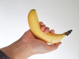 Isolated white photo of a woman's hand holding a cavendish yellow banana.