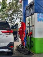 West Java, Indonesia in July 2022. A Pertamina female officer refueling a car. photo