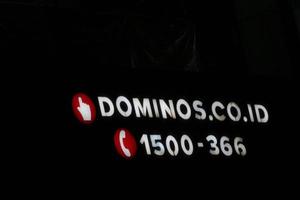 Bekasi, Indonesia in July 2022. Domino's Pizza logo shining brightly at night against the dark night sky. photo