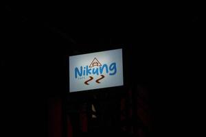 Bekasi, Indonesia in July 2022. Nikung Cafe logo glowing in the dark. photo