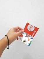 West Java, Indonesia in January 2023. Isolated white photo of a hand holding the KAKOO product brand tag