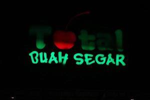Bekasi, Indonesia in July 2022. The TOTAL Buah Segar logo shining brightly at night against the dark night sky. photo