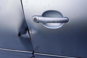 Car door with break-in marks from a crowbar near the handle. photo