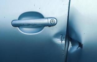 Car door with break-in marks from a crowbar near the handle. photo