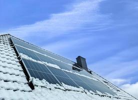 paneles solares que producen energía limpia en un techo cubierto de nieve de una casa residencial. foto