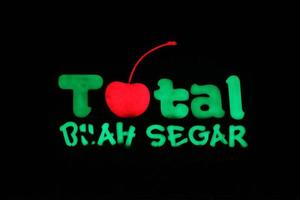 Bekasi, Indonesia in July 2022. The TOTAL Buah Segar logo shining brightly at night against the dark night sky. photo