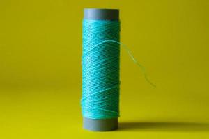 Isolated photo of a ball of light blue thread above and in front of a yellow background.