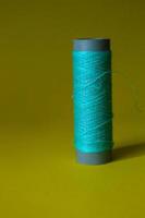 Isolated photo of a ball of light blue thread above and in front of a yellow background.