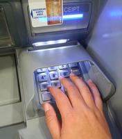 West Java, Indonesia in July 2022. A hand is pressing the numeric keypad on an ATM machine photo