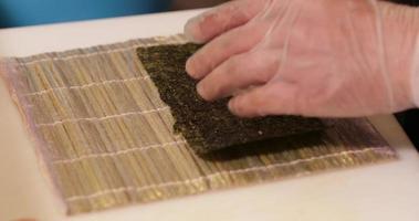 Spreading Cooked Sushi Rice On A Seaweed Wrap - Sushi Making - close up, slow motion video