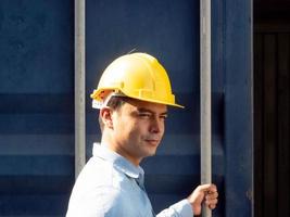 Engineer  foreman employee person yellow hardhat helmet safety standing portrait check up cargo open container logistic warehouse factory import export shipping work job storage uniform technology photo