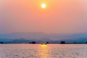 Fisherman driving a boat to home at sunset photo