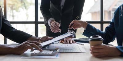 gente de negocios reunida usando computadora portátil, calculadora, cuaderno, papel gráfico del mercado de valores para planes de análisis para mejorar la calidad el próximo mes. conferencia discusión concepto corporativo foto