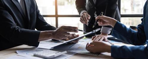 gente de negocios reunida usando computadora portátil, calculadora, cuaderno, papel gráfico del mercado de valores para planes de análisis para mejorar la calidad el próximo mes. conferencia discusión concepto corporativo foto