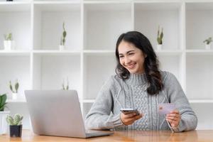 Happy asian Business woman pay online using mobile phone at the office. photo