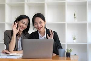 Two young Asian business woman talk, consult, discuss working with new startup project idea presentation analyze plan marketing and investment in the office. photo