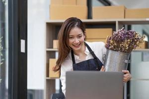 A portrait of a small startup, an SME owner, an Asian female entrepreneur checking orders to arrange the produce before packing the products in the inner boxes with the customers. Freelance concepts photo