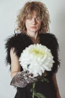 Close up curly haired model with dahlia in studio portrait picture photo