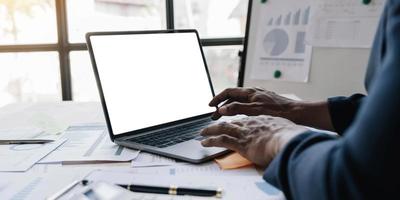 Close-up image, Businessman or male financial consultant working on laptop computer, typing on keyboard, checking the financial data. laptop blank screen mockup. photo